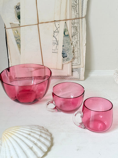 Trio of antique cranberry glass with sugar bowl, teacup, coffee can, clear glass handles and deep pink glass