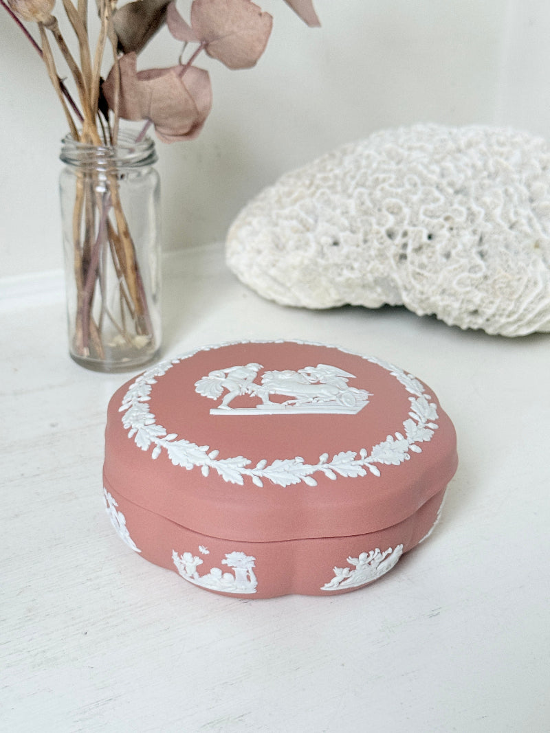 Rare vintage Wedgwood Jasperware round lidded trinket box in terracotta rose pink, with a central classical cameo scene and white laurel wreath border.