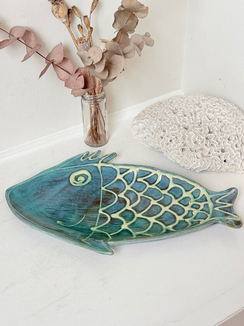 Barbados studio pottery fish platter in turquoise and sea green glaze photographed on a white surface