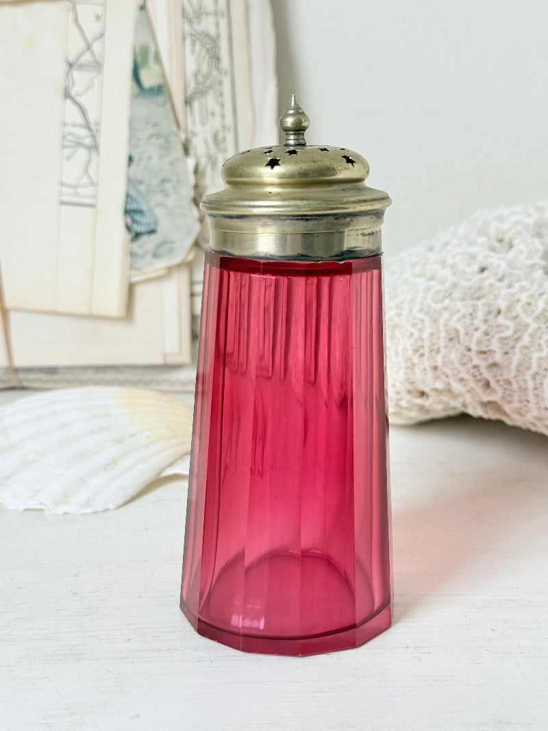 Antique cranberry glass sugar shaker with ribbed optic body, pierced metal top, star holes and deep pink glass