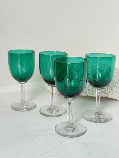 Antique set of four Bristol green liqueur glasses with clear stems, photographed on a white surface