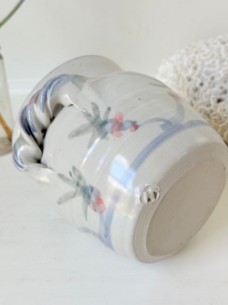 Vintage studio pottery utensil pot with hand painted floral decoration and applied handle detail, photographed on a white surface