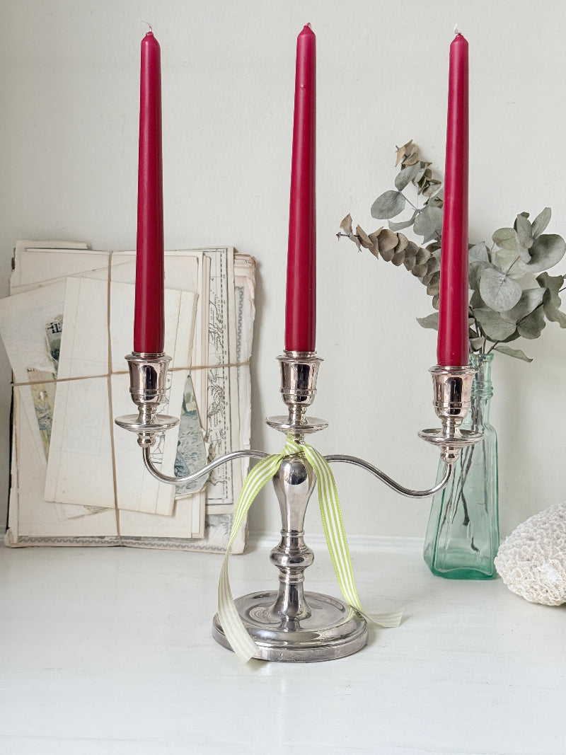 Silver plate three light candelabra with curved arms and domed base holding red taper candles
