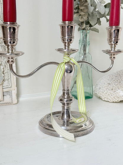 Silver plate three light candelabra with curved arms and domed base holding red taper candles