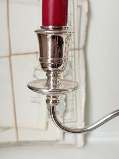 Silver plate three light candelabra with curved arms and domed base holding red taper candles