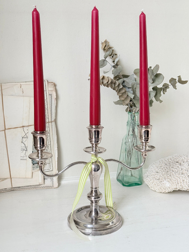 Silver plate three light candelabra with curved arms and domed base holding red taper candles