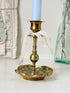 Brass candlestick with turned baluster stem and scalloped embossed base photographed on a white surface
