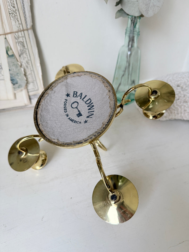 Brass five light candelabra with scrolled arms and a central ring handle on a domed base, photographed on a white surface
