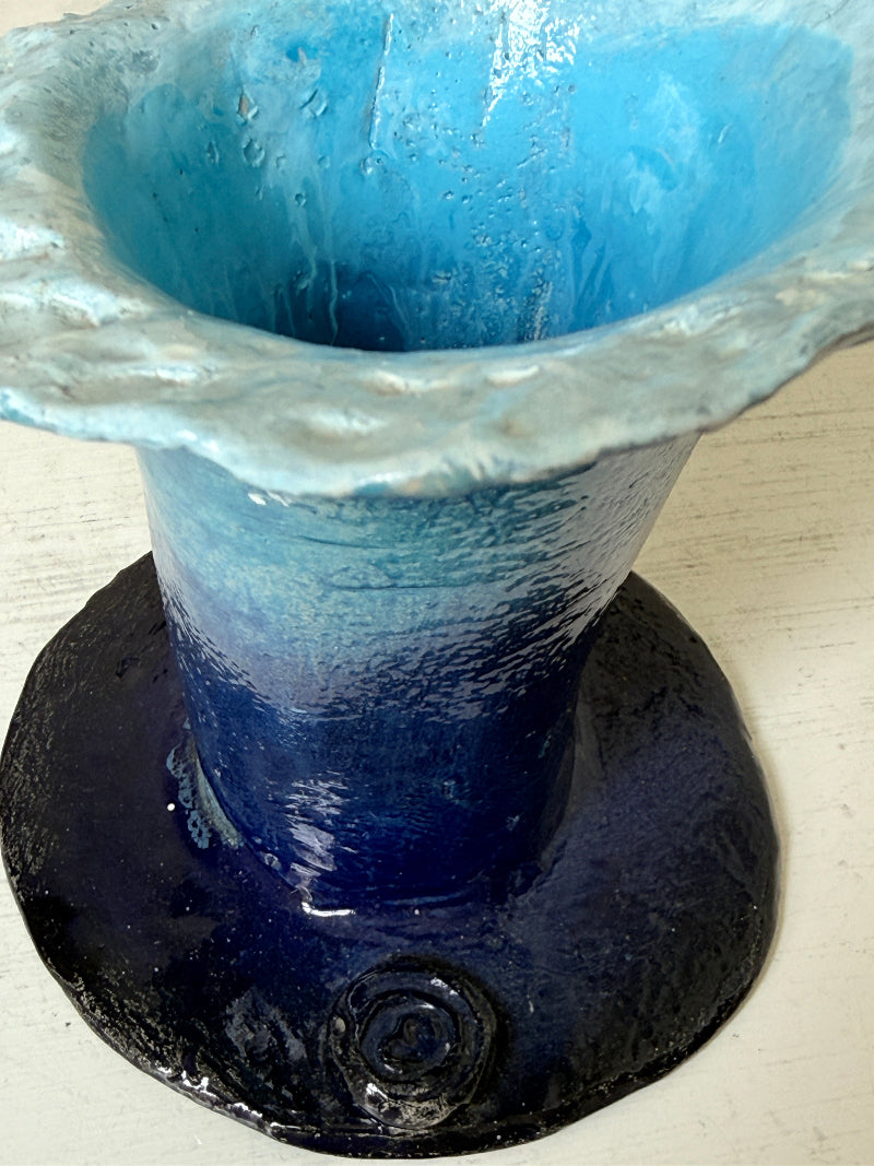 Handmade studio pottery trumpet vase in ombre blue with a frilled rim, photographed on a white surface
