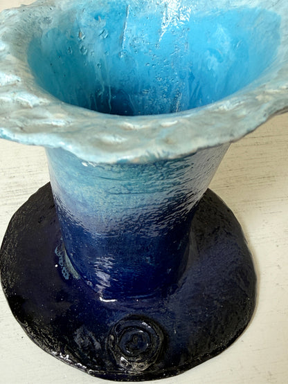 Handmade studio pottery trumpet vase in ombre blue with a frilled rim, photographed on a white surface