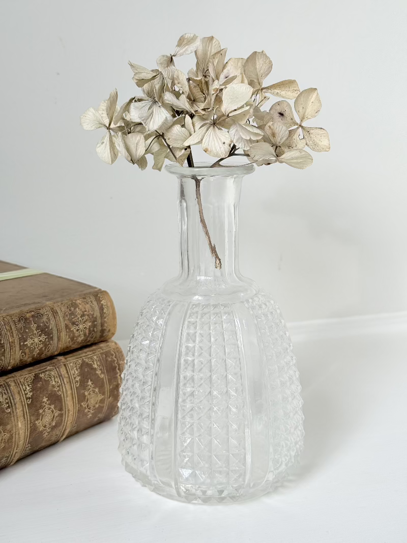 Vintage clear glass vase with textured surface, styled with dried flowers on a white background