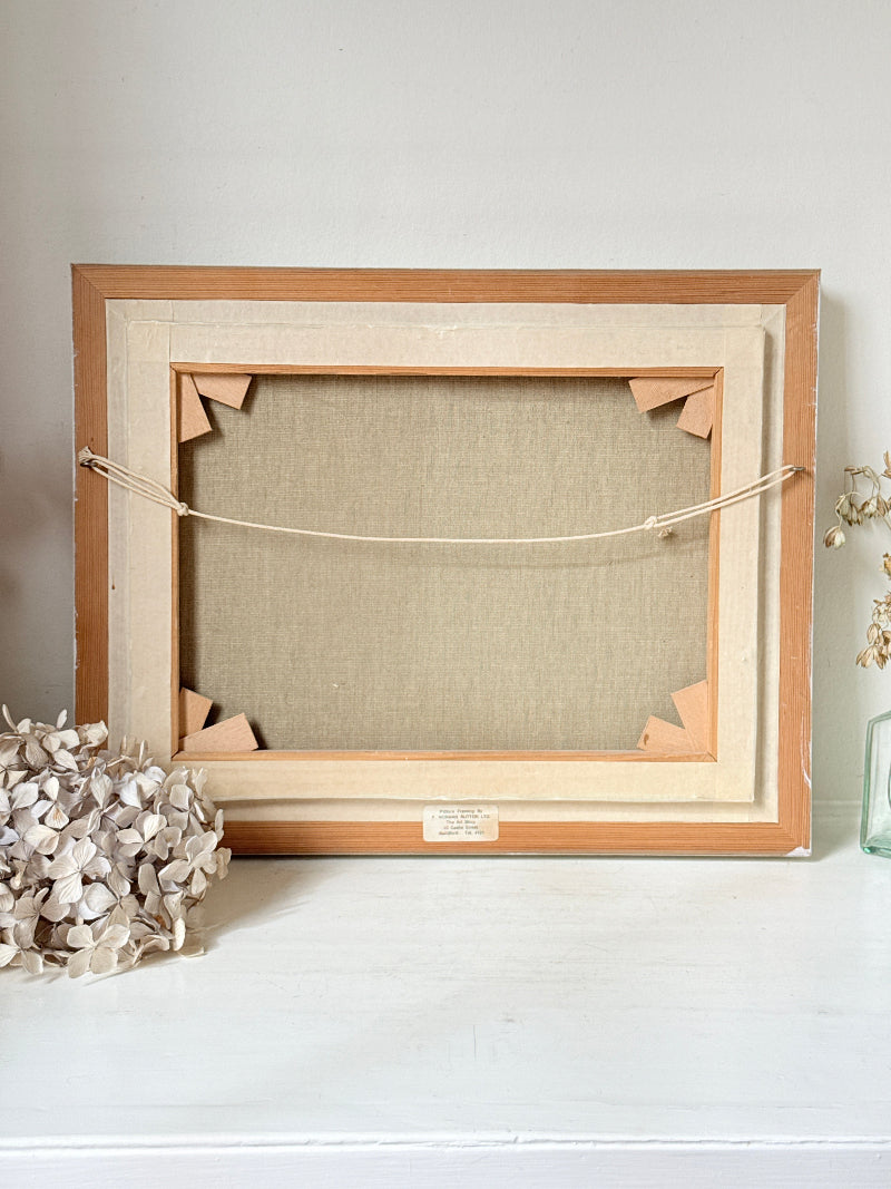 The back of a wooden picture frame with a linen canvas backing, displayed on a white surface against a light gray wall.