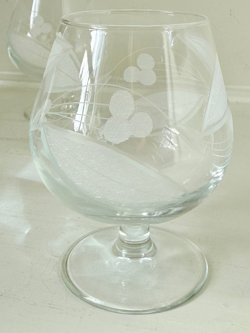 Set of six vintage etched Bailey’s glasses with rounded bowls and short stems, photographed on white surface.