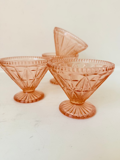 Set of four vintage pressed glass coral dishes with geometric pattern and flared form, photographed on white surface.