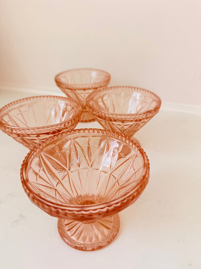 Set of four vintage pressed glass coral dishes with geometric pattern and flared form, photographed on white surface.