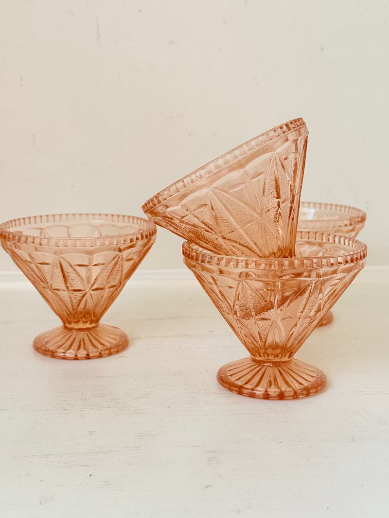 Set of four vintage pressed glass coral dishes with geometric pattern and flared form, photographed on white surface.