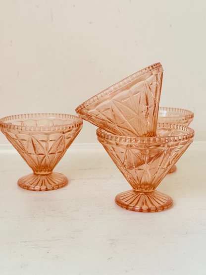 Set of four vintage pressed glass coral dishes with geometric pattern and flared form, photographed on white surface.