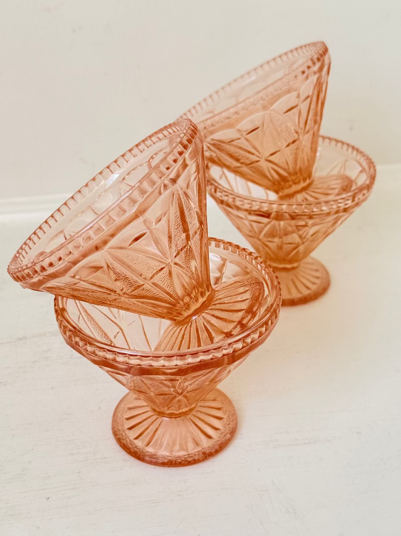 Set of four vintage pressed glass coral dishes with geometric pattern and flared form, photographed on white surface.