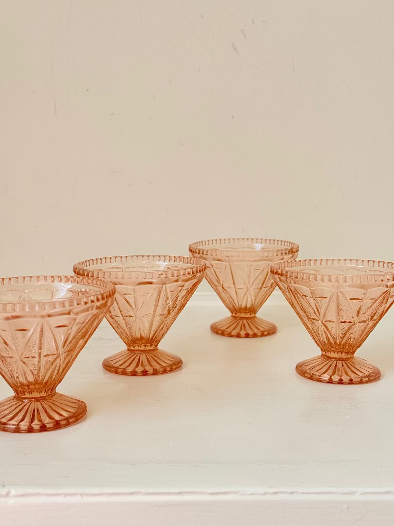 Set of four vintage pressed glass coral dishes with geometric pattern and flared form, photographed on white surface.