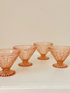 Set of four vintage pressed glass coral dishes with geometric pattern and flared form, photographed on white surface.