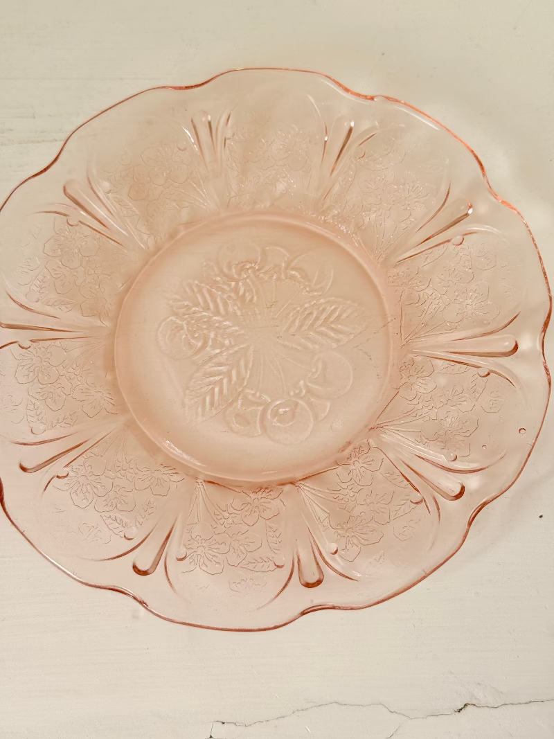 Set of seven vintage pressed glass coral plates with cherry and blossom motif, photographed on white surface.