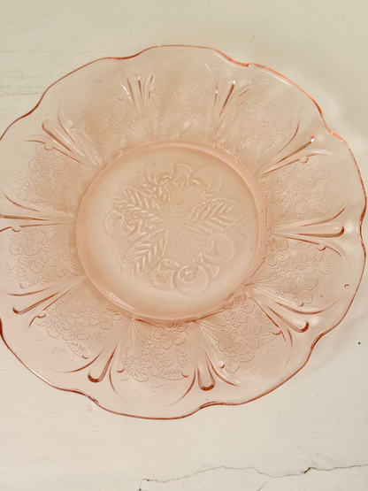 Set of seven vintage pressed glass coral plates with cherry and blossom motif, photographed on white surface.