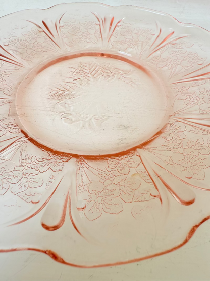 Set of seven vintage pressed glass coral plates with cherry and blossom motif, photographed on white surface.