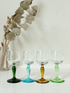 Vintage set of four etched liqueur glasses with colourful stems in green, amber, blue, and turquoise, photographed on a white surface
