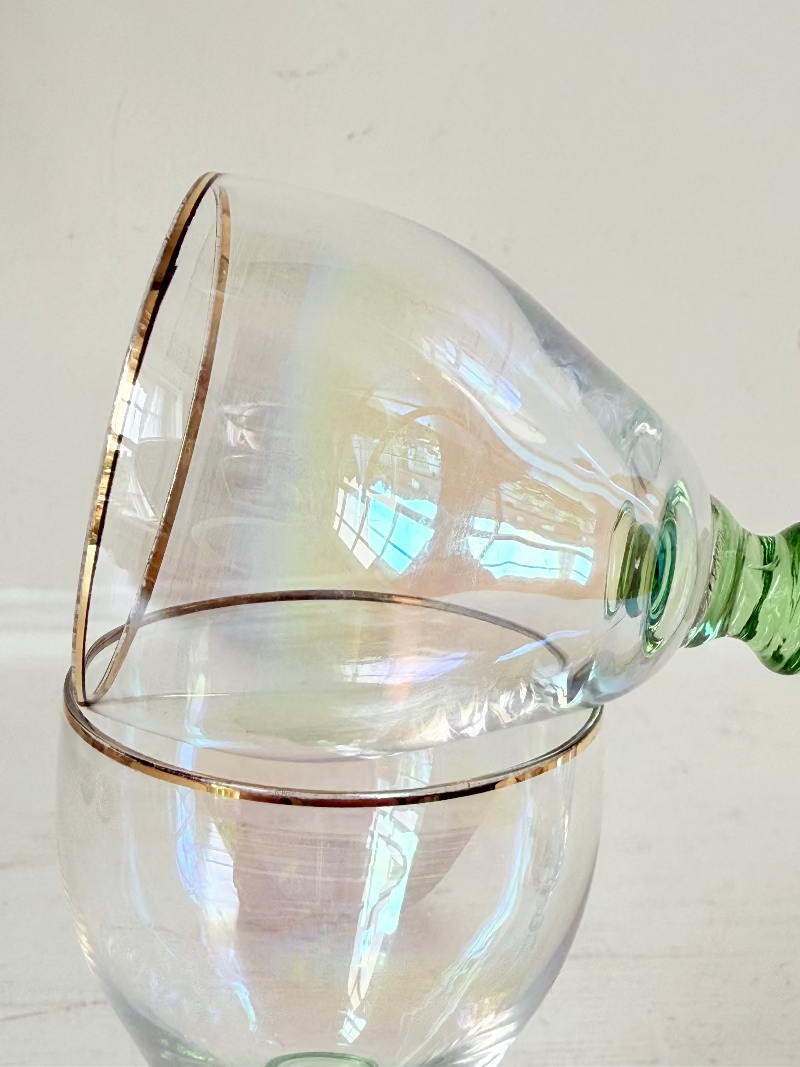 Vintage trio of iridescent shot glasses with green stems and gilt rims, photographed on a white surface