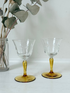 Pair of vintage liquor glasses with clear bowls and amber stems, photographed on white surface.