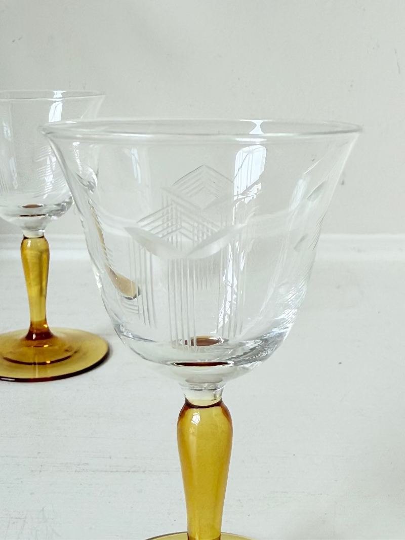 Pair of vintage liquor glasses with clear bowls and amber stems, photographed on white surface.