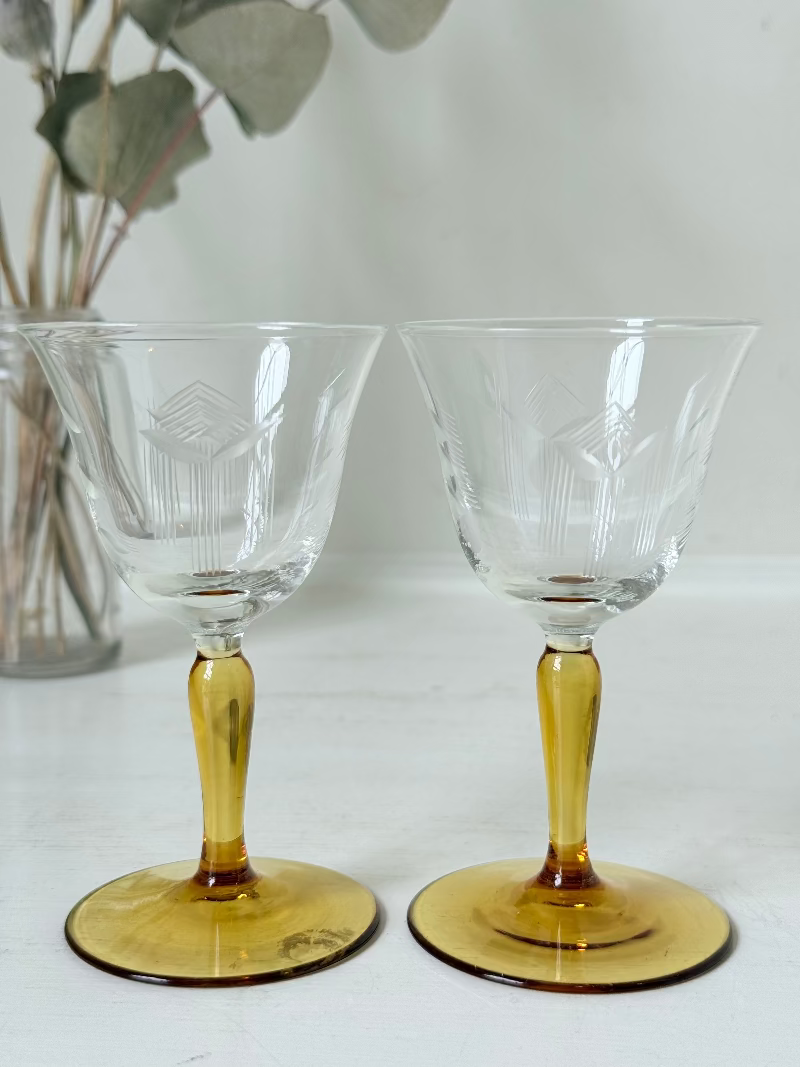 Pair of vintage liquor glasses with clear bowls and amber stems, photographed on white surface.
