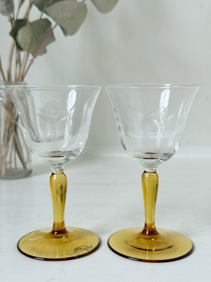 Pair of vintage liquor glasses with clear bowls and amber stems, photographed on white surface.
