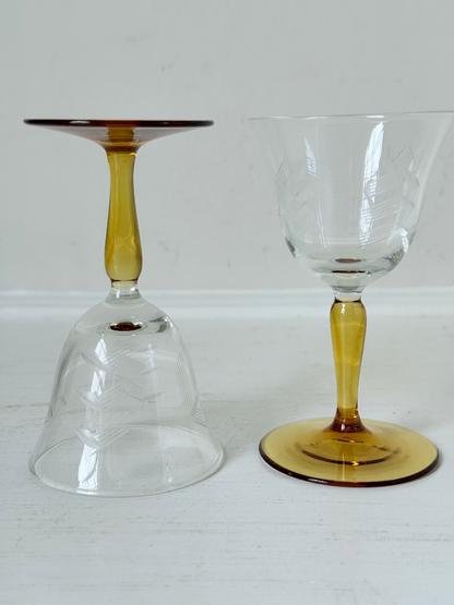 Pair of vintage liquor glasses with clear bowls and amber stems, photographed on white surface.