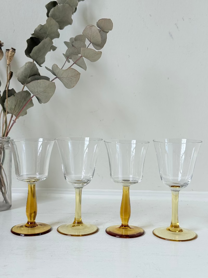 Two pairs of vintage liquor glasses with clear bowls and amber stems, photographed on white surface.