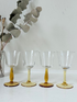 Two pairs of vintage liquor glasses with clear bowls and amber stems, photographed on white surface.