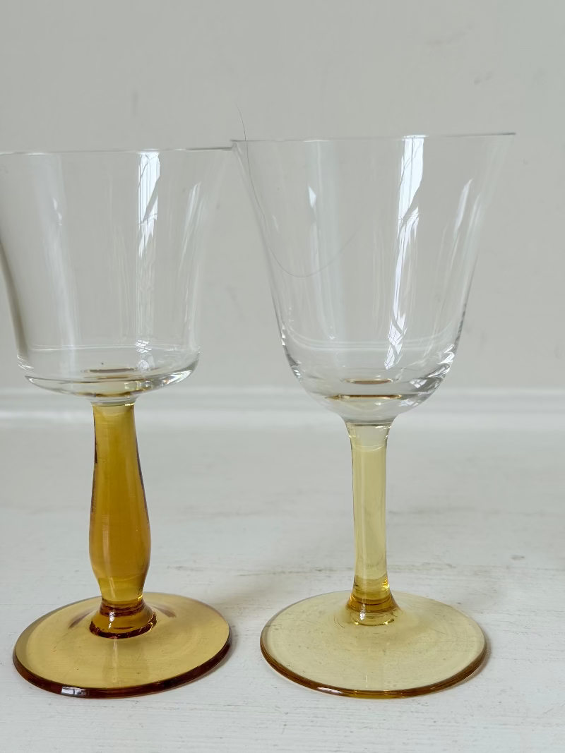 Two pairs of vintage liquor glasses with clear bowls and amber stems, photographed on white surface.