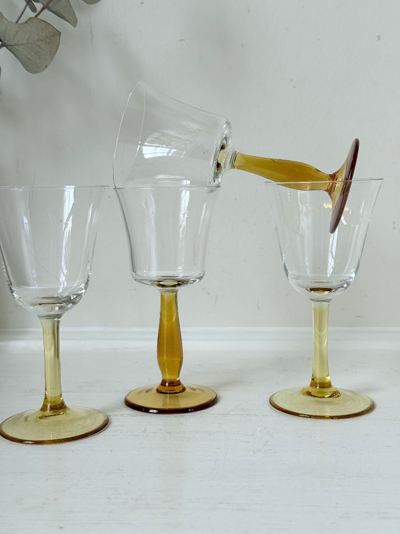 Two pairs of vintage liquor glasses with clear bowls and amber stems, photographed on white surface.