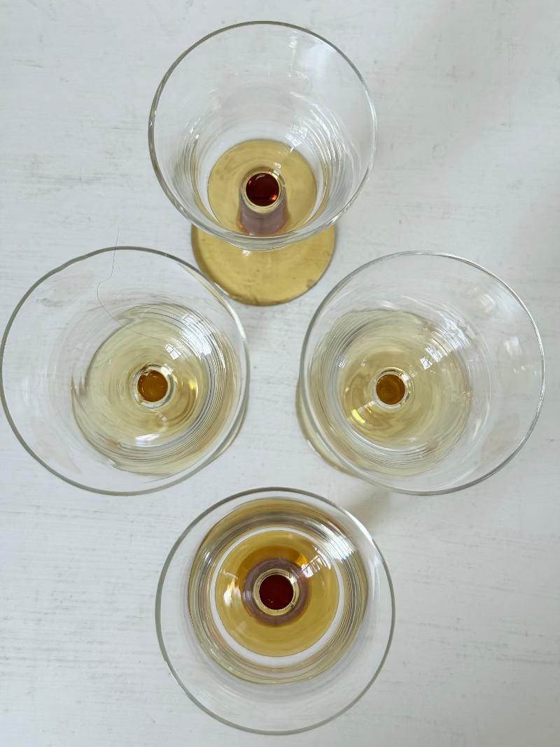 Two pairs of vintage liquor glasses with clear bowls and amber stems, photographed on white surface.