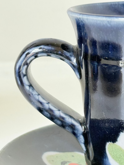 Vintage studio pottery coffee cans with matching saucers in navy glaze and floral motifs, set of four, photographed on a white surface