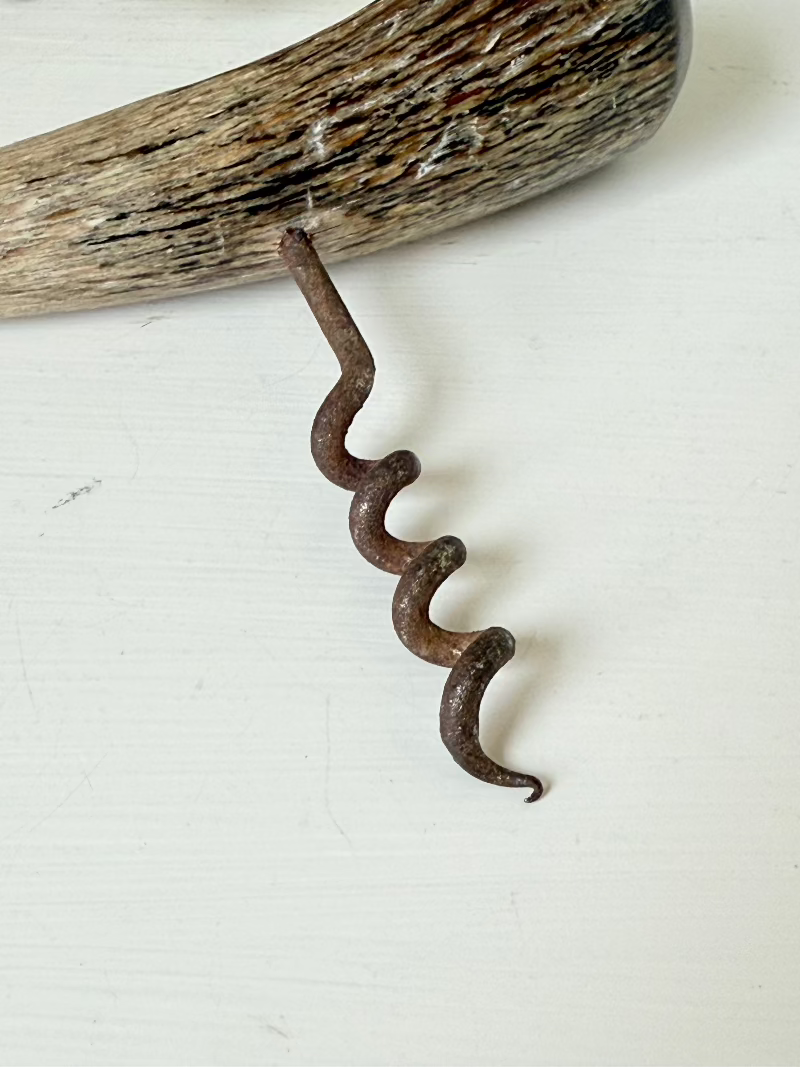 vintage corkscrew with natural horn handle and aged steel spiral on white surface