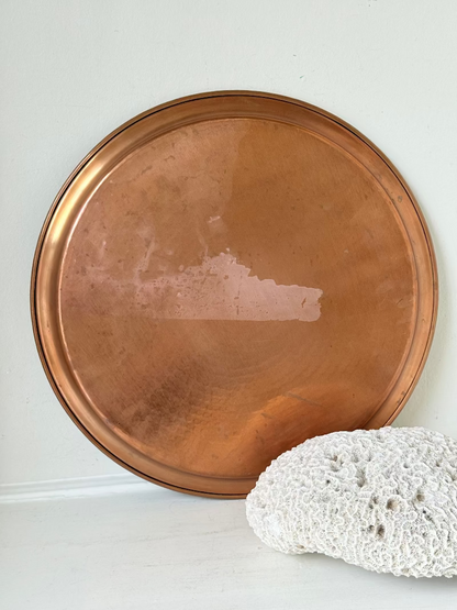 Lakeland Borrowdale hammered copper tray with warm patina, photographed on a white surface beside dried stems.