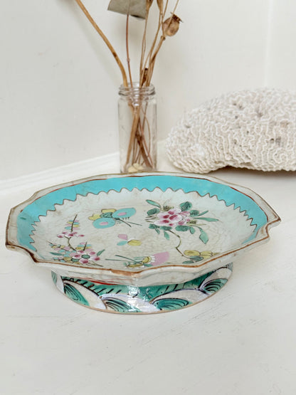 Antique ceramic footed dish with turquoise floral and bird design, photographed on a white surface.