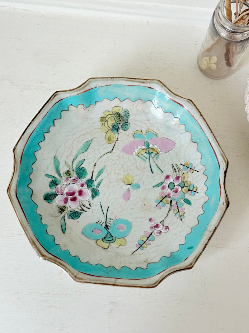 Antique ceramic footed dish with turquoise floral and bird design, photographed on a white surface.