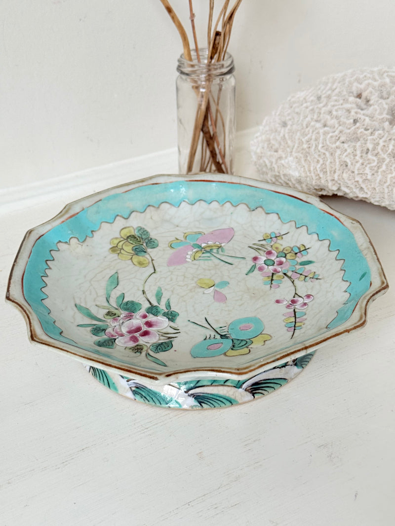 Antique ceramic footed dish with turquoise floral and bird design, photographed on a white surface.