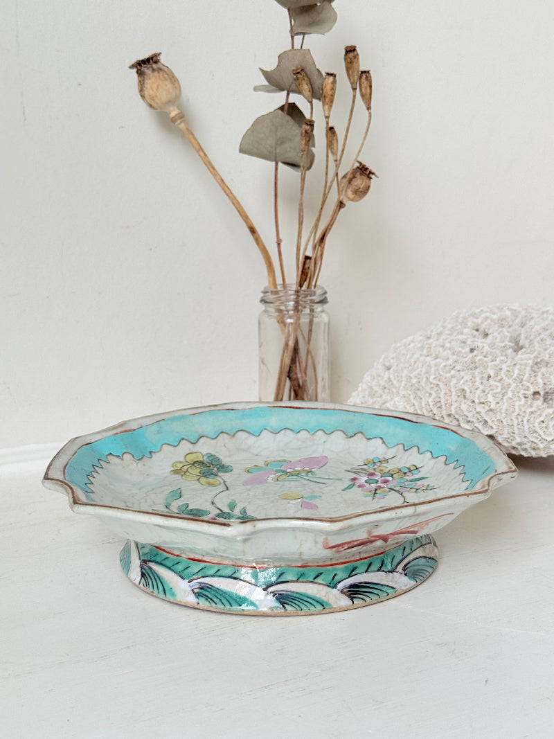 Antique ceramic footed dish with turquoise floral and bird design, photographed on a white surface.