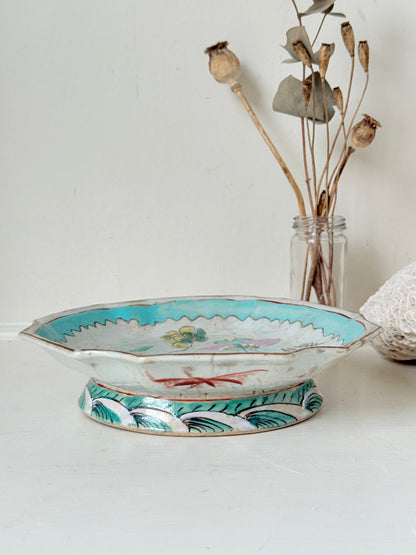 Antique ceramic footed dish with turquoise floral and bird design, photographed on a white surface.