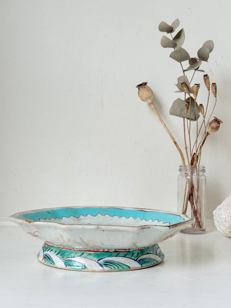 Antique ceramic footed dish with turquoise floral and bird design, photographed on a white surface.