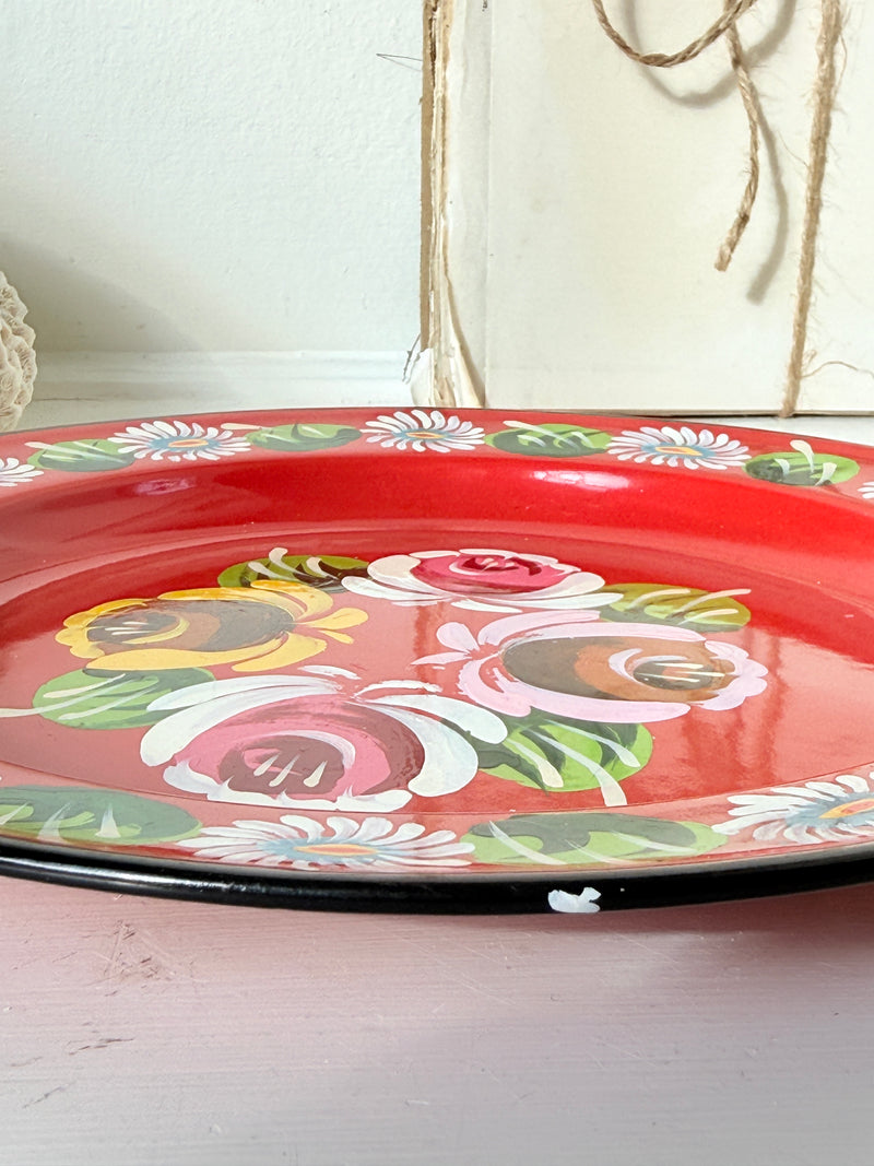 Close up of hand painted roses at the centre of a red bargeware plate
