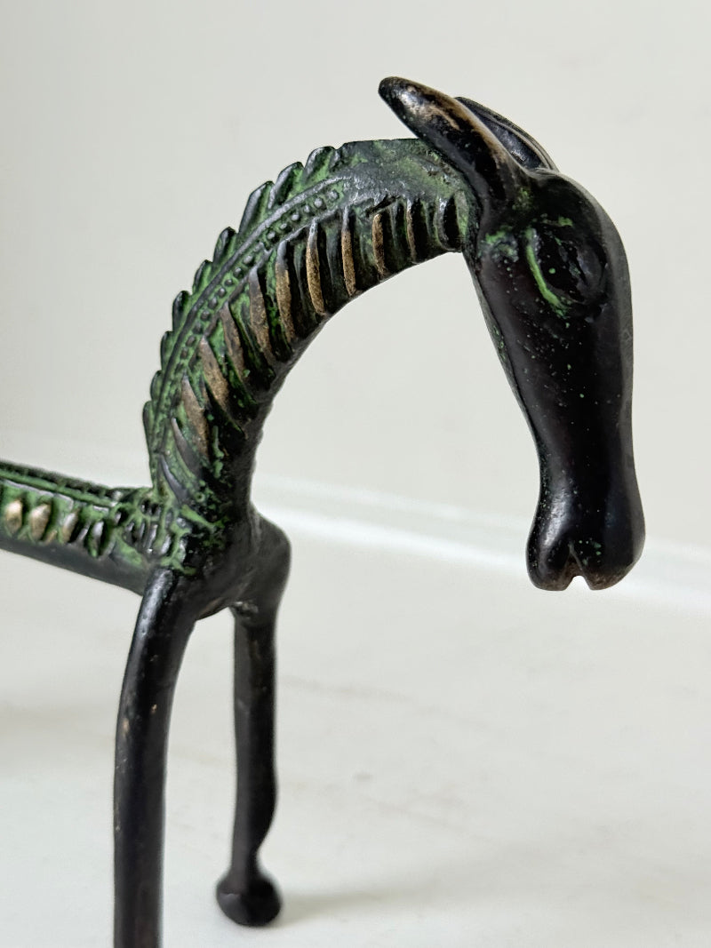 Vintage bronze horse sculpture with green patina, photographed on a white surface.